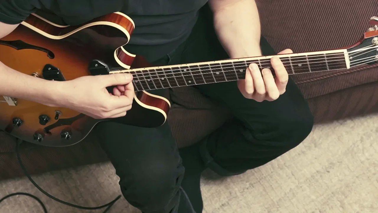 Close-up from a Bootcamp lesson video showing a barre chord being fretted